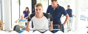 Jongen met gewichten tijdens sporten in zaal | Fysio Stenia Zeist